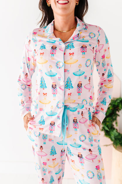 Woman wearing a light pink bamboo pajama set featuring Christmas trees, ballerinas, and nutcrackers