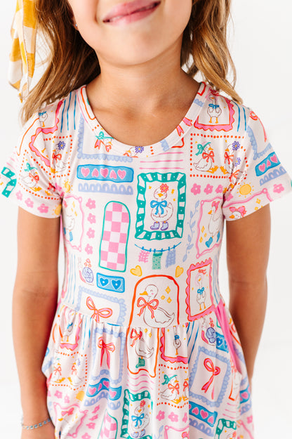 Child wearing a colorful patterned bamboo dress with geese on a white background