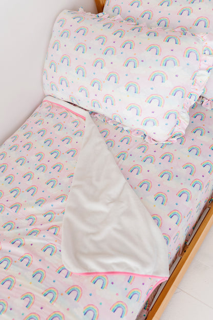 Children's bamboo bedding set with watercolor rainbow pattern on a bed.