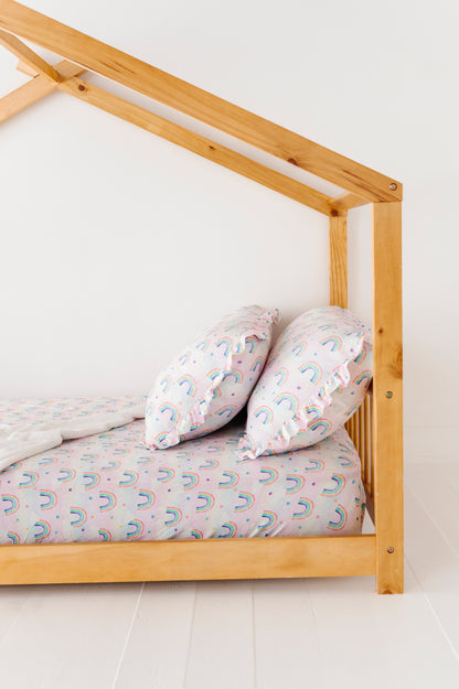 Wooden bed frame with a mattress and pillows against a white wall