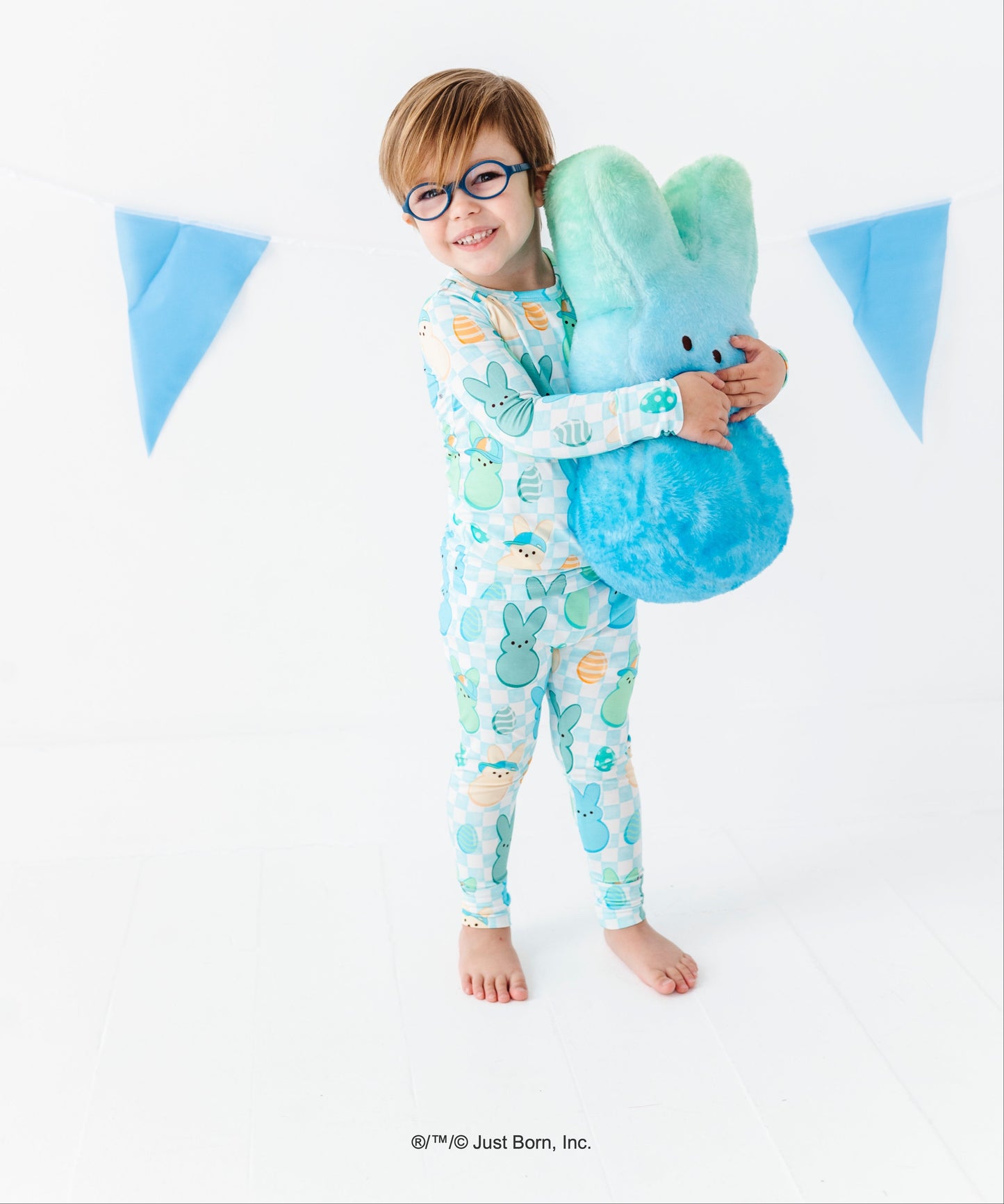Child wearing  patterned pajamas holding a plush PEEPS® toy against a white background