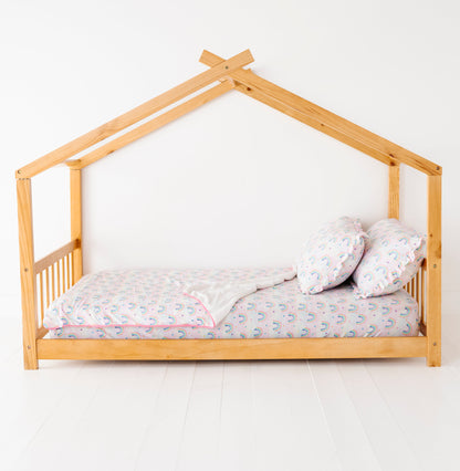 Wooden children's bed with a rainbow bamboo twin sheet and matching bamboo ruffle pillowcases on a white background