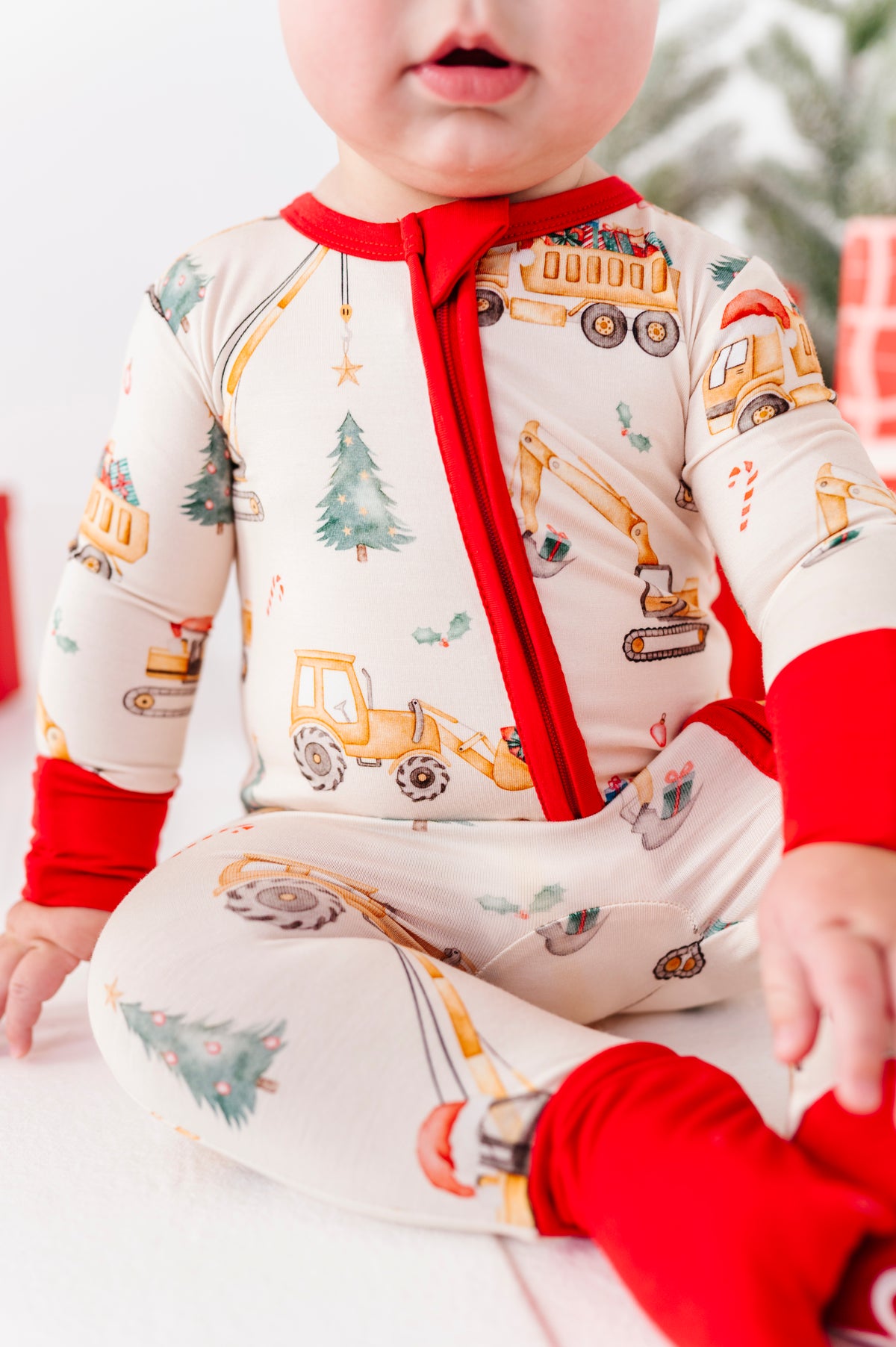A close-up detail shot of a Christmas construction print featuring construction trucks, excavators, etc moving Christmas trees 