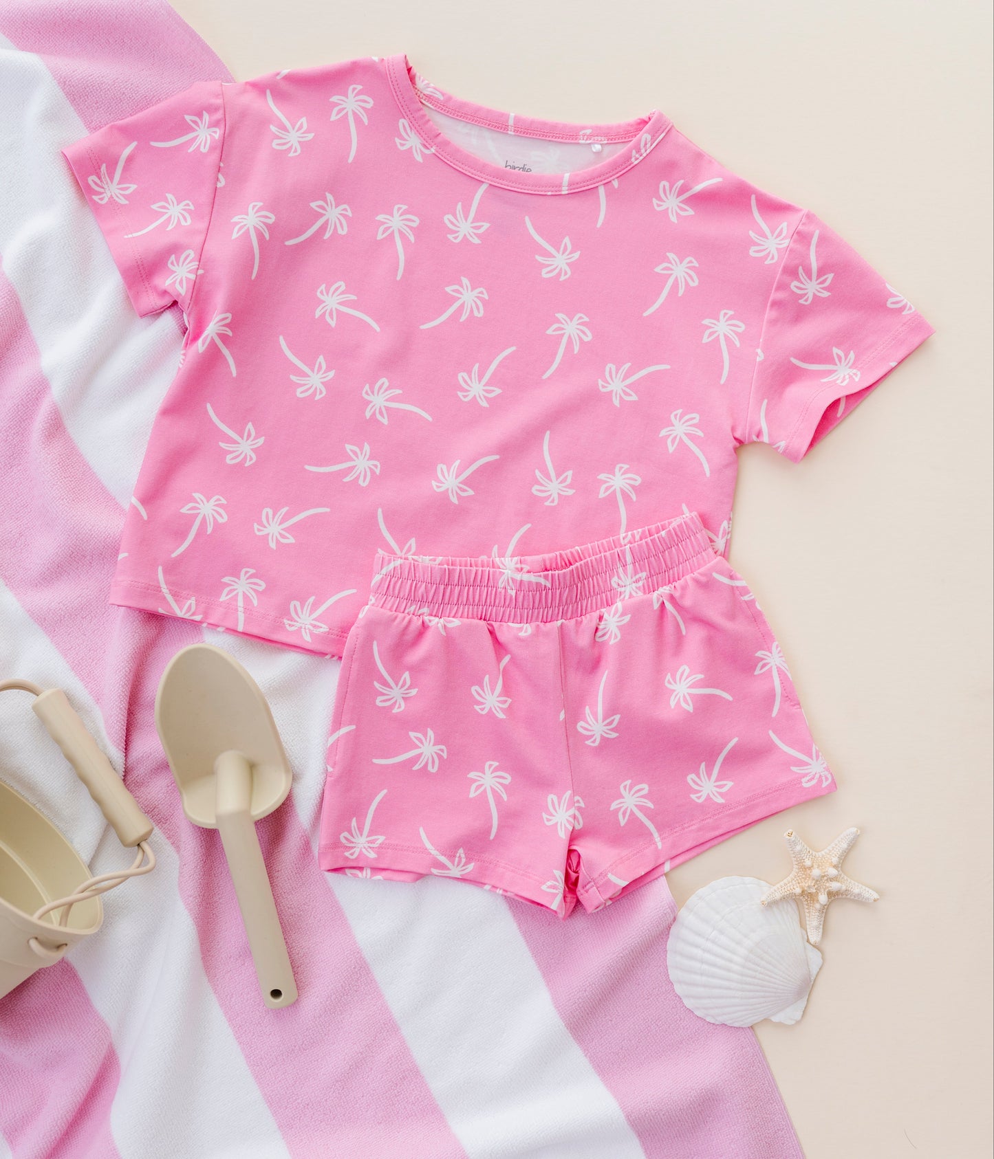 Pink children's outfit with white palm tree pattern on a light pink background
