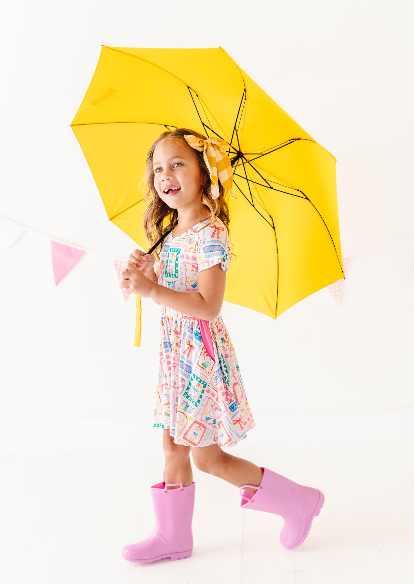 Child holding a yellow umbrella on a white background
