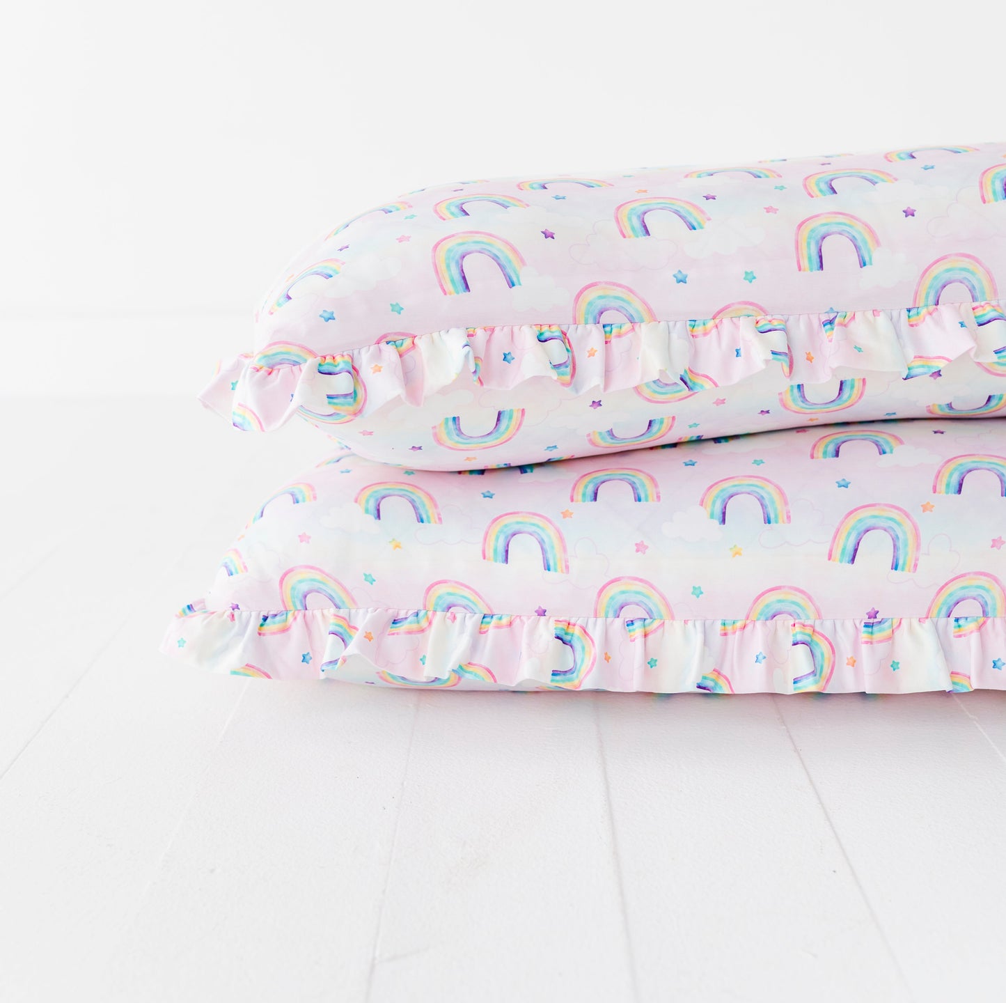 Stacked pillows with watercolor rainbow pattern on a white background