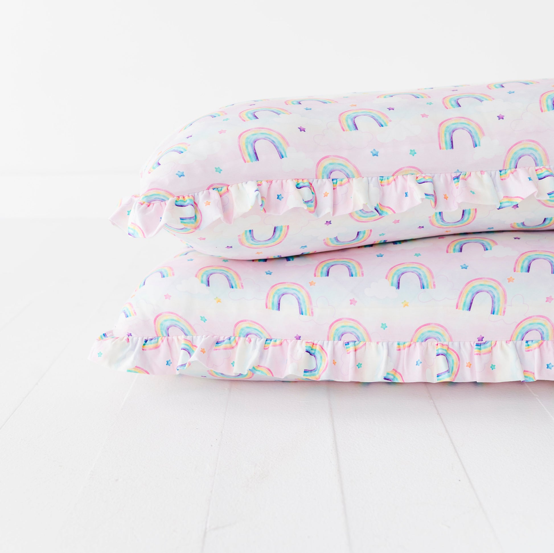 Stacked pillows with watercolor rainbow pattern on a white background