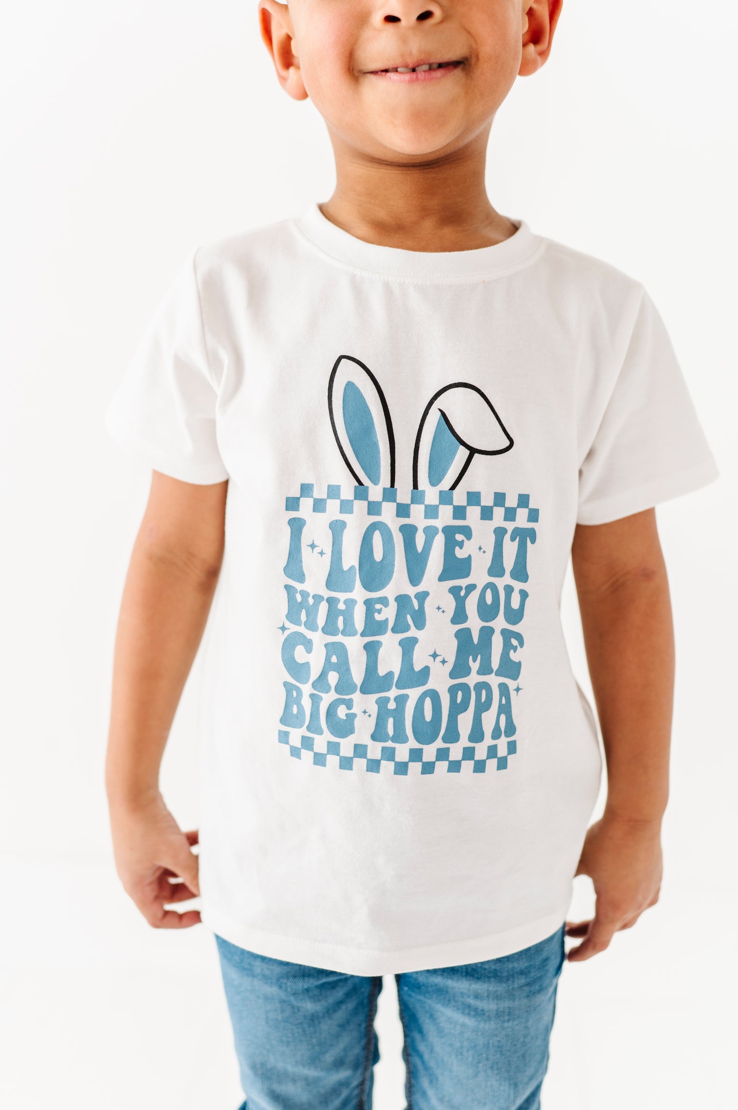 Child wearing a white t-shirt with a blue graphic and text on a white background