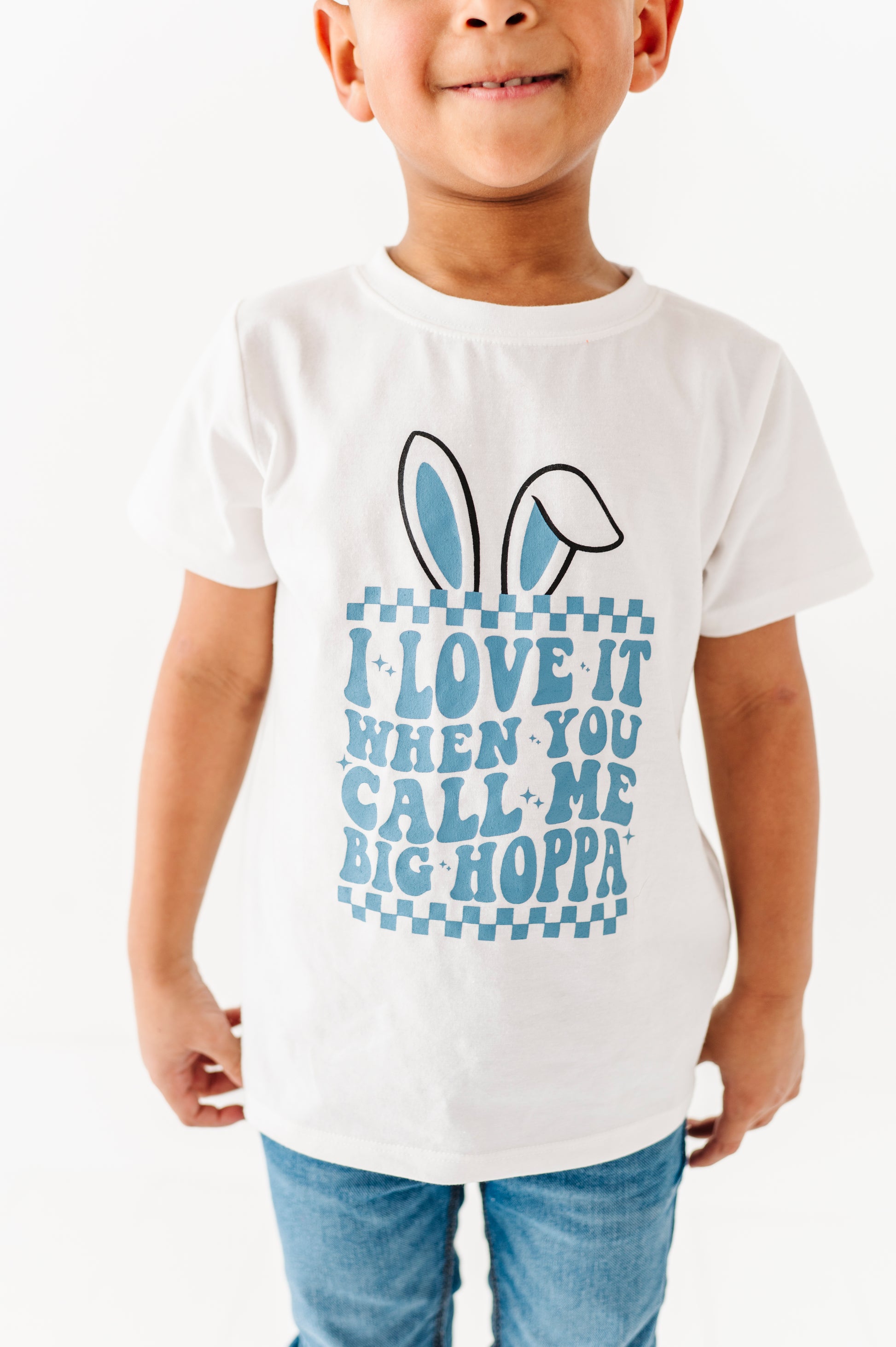 Child wearing a white t-shirt with a blue graphic and text on a white background