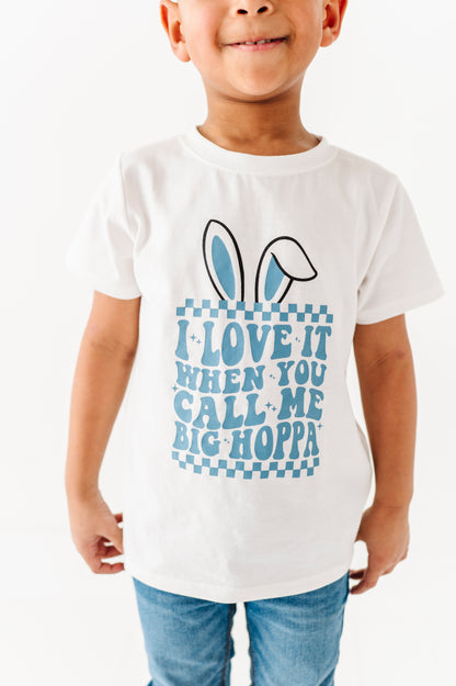 Child wearing a white t-shirt with a blue graphic and text on a white background