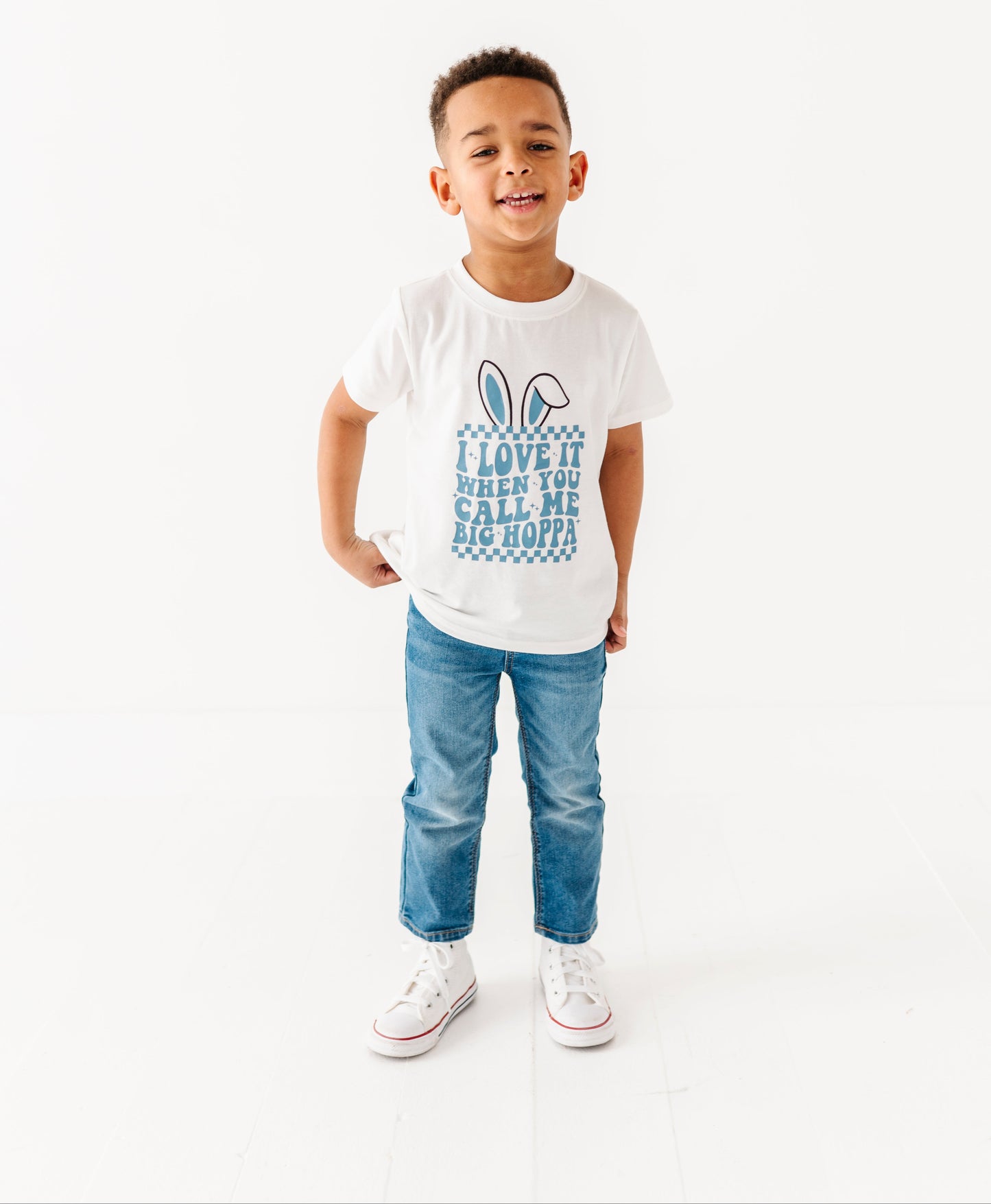 Child wearing a white t-shirt with text and graphics, standing against a white background
