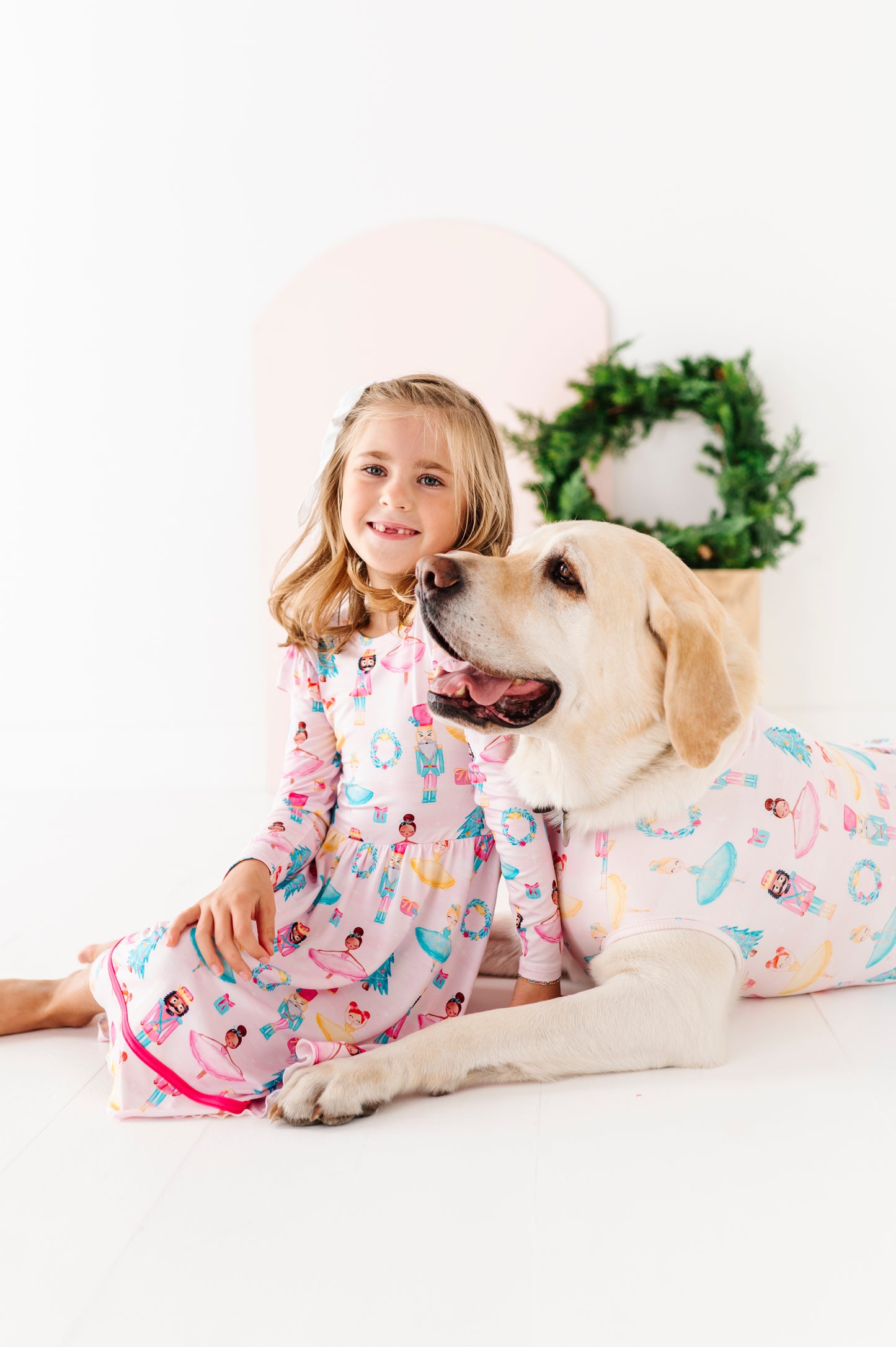 Girl and dog wearing matching bamboo Christmas outfits on a white background