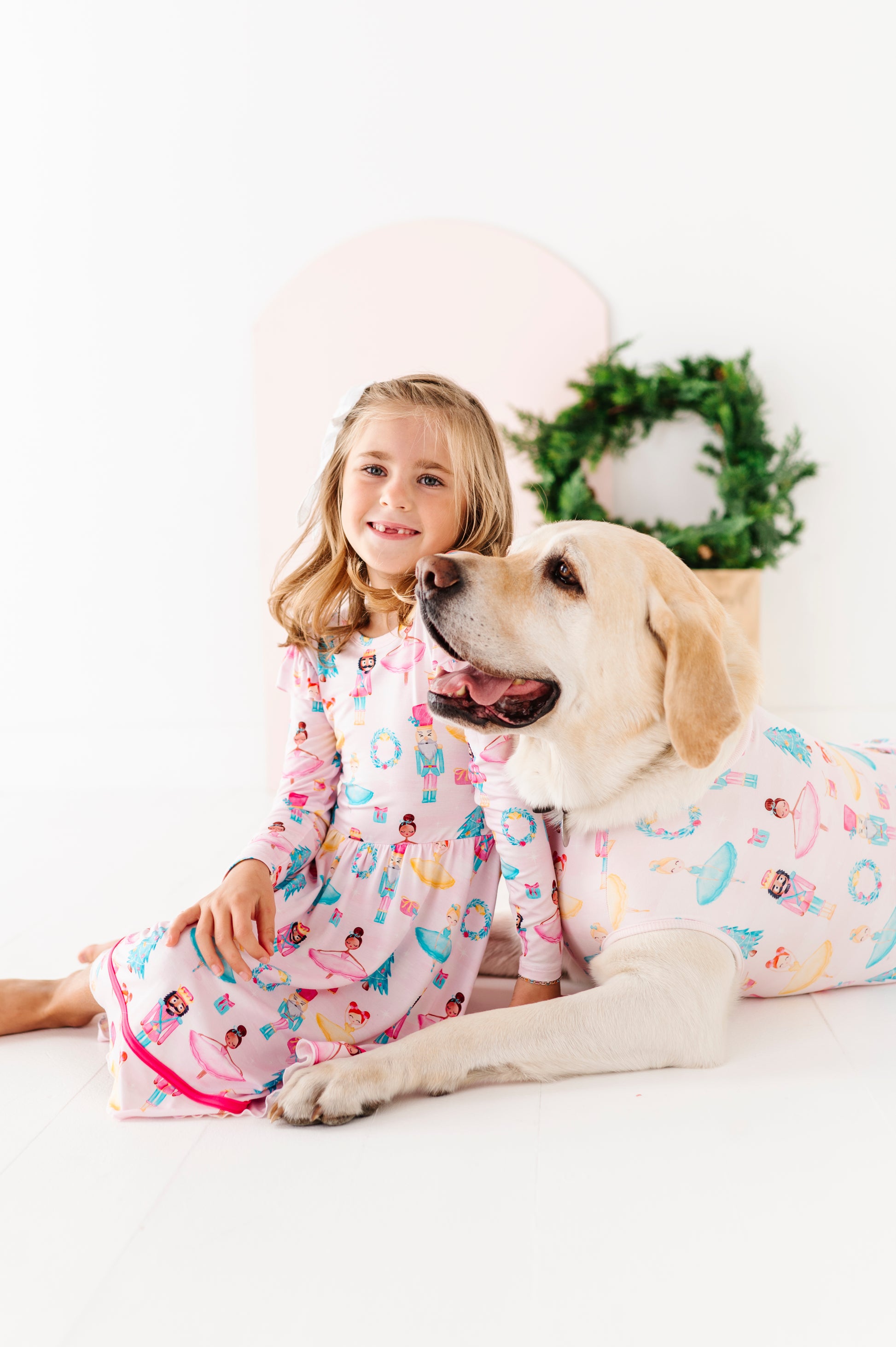 Girl and dog wearing matching bamboo Christmas outfits on a white background