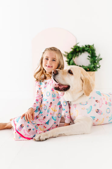 Girl and dog wearing matching bamboo Christmas outfits on a white background