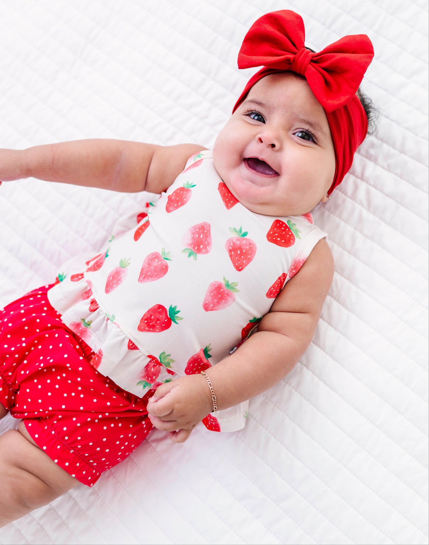 Baby wearing a red and white outfit with a large bow on a white background