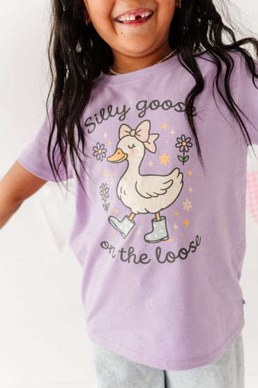 Child wearing a purple t-shirt with a goose graphic and text on a white background