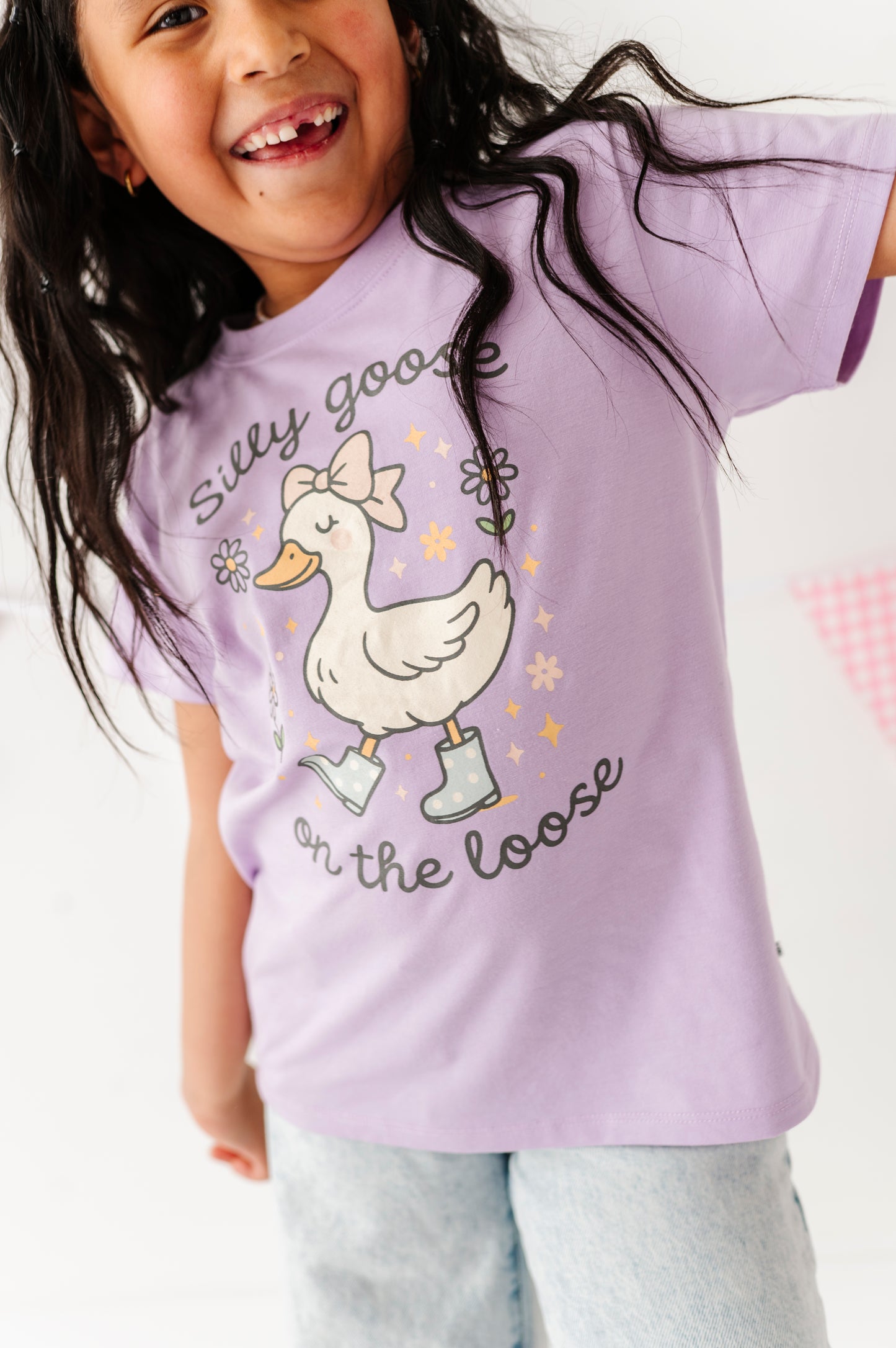 Child wearing a purple t-shirt with a goose graphic and text on a white background