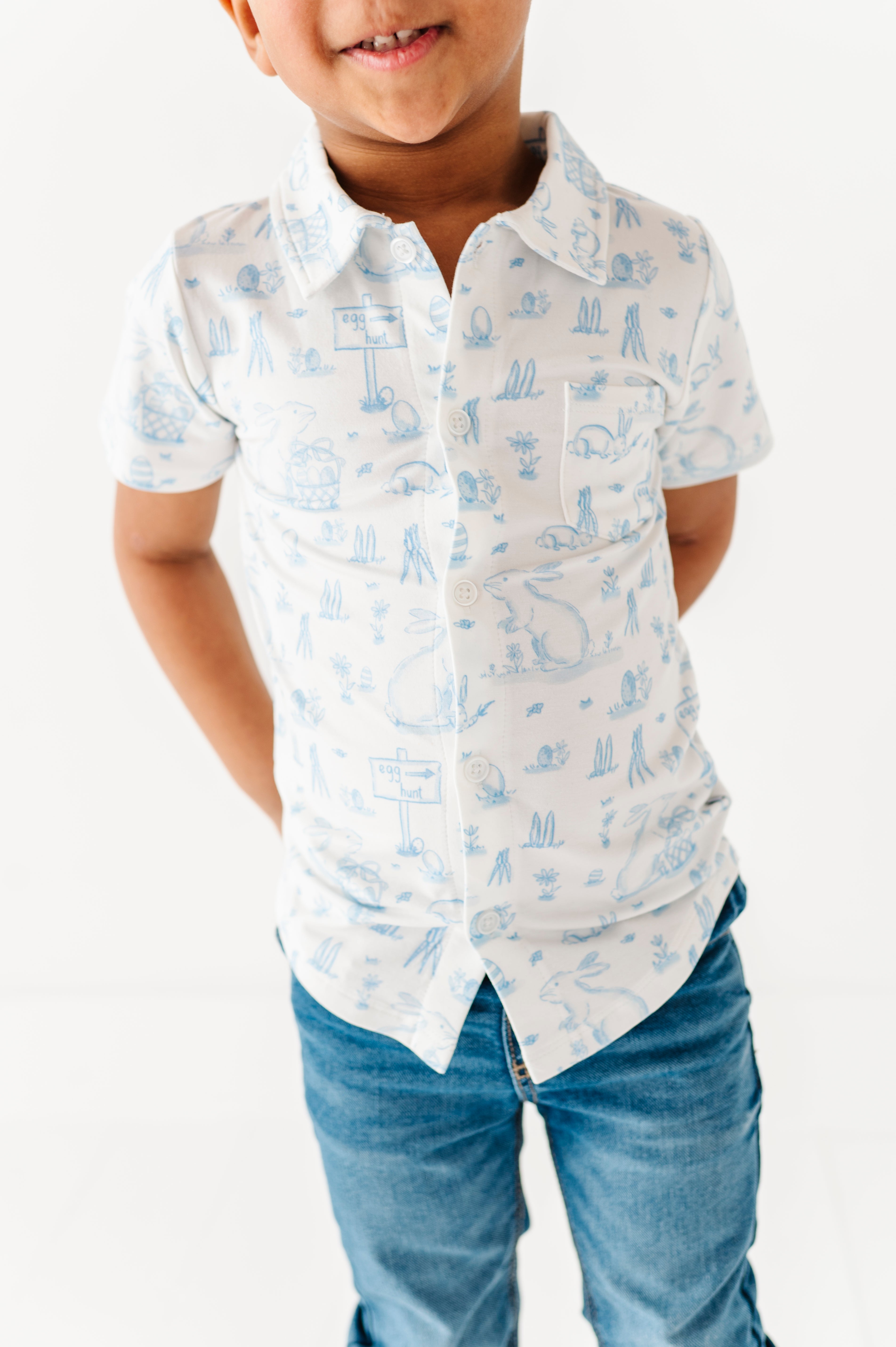 Child wearing a white shirt with blue easter pattern and blue jeans on a white background