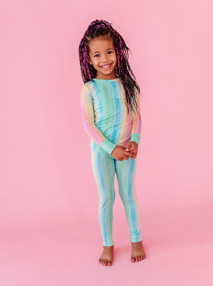 Little girl wearing a colorful striped bamboo pajama on a pink background