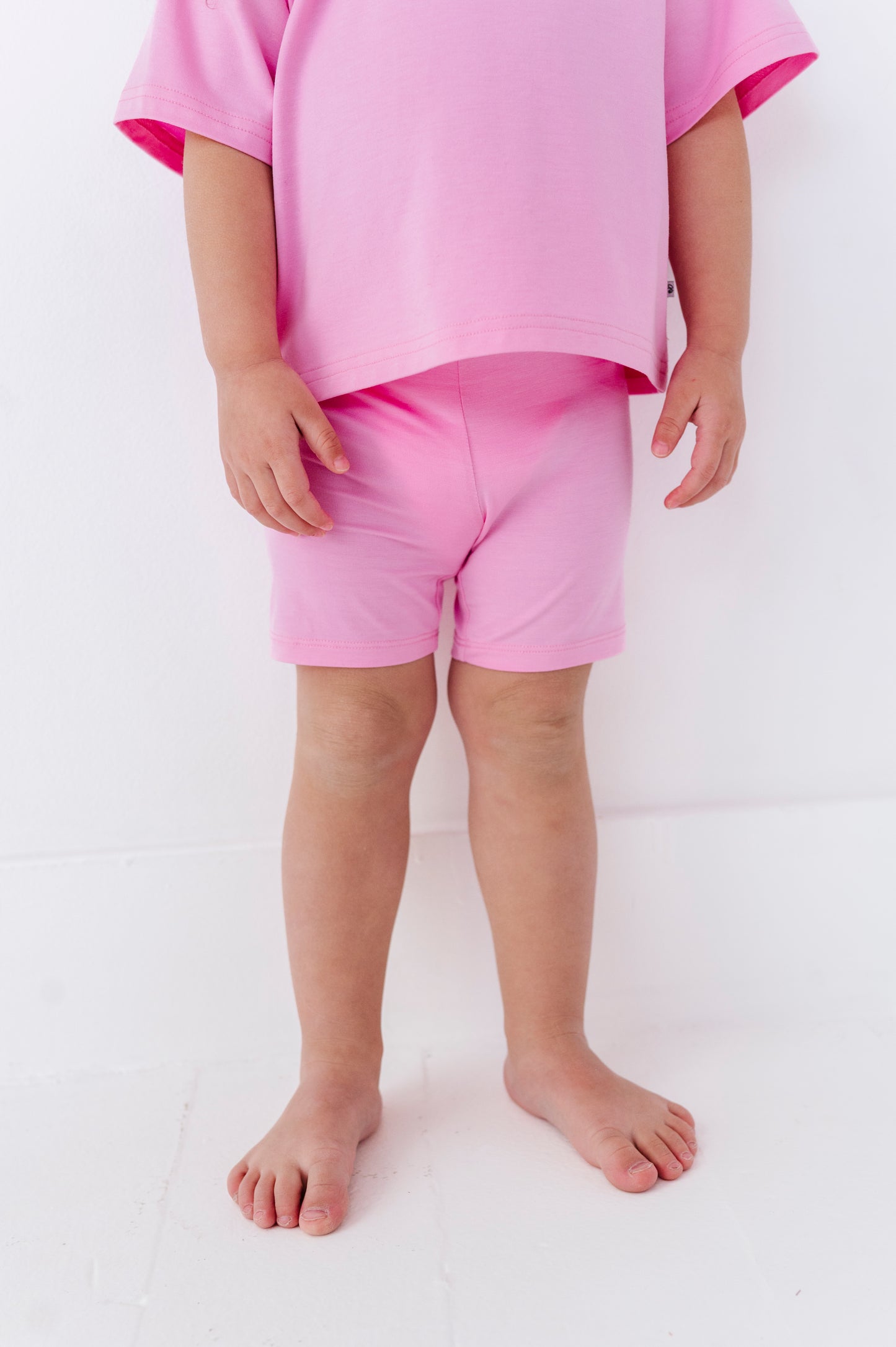 Child wearing pink bamboo biker shorts and a matching top on a white background