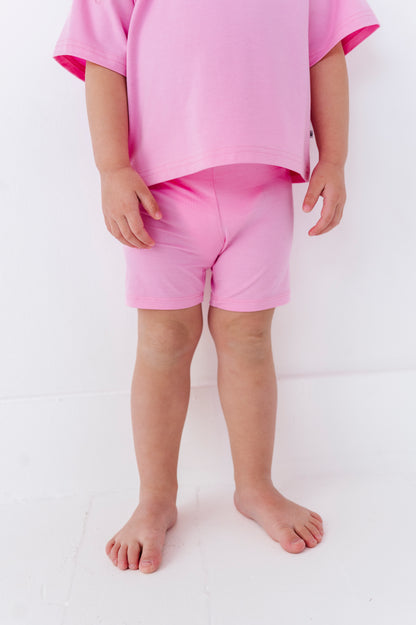 Child wearing pink bamboo biker shorts and a matching top on a white background