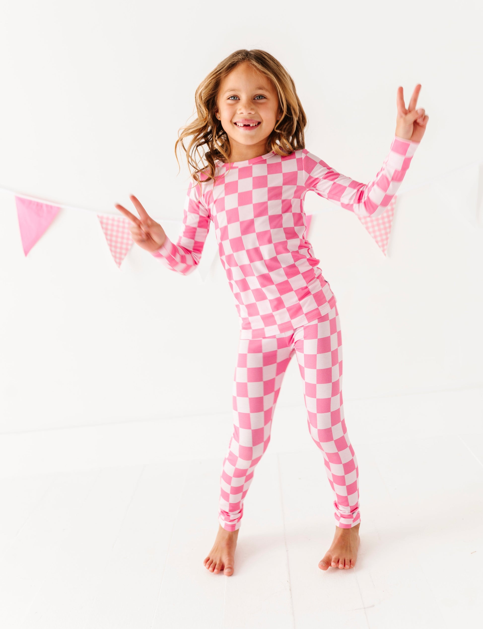 Child wearing pink checkered bamboo pajamas on a white background