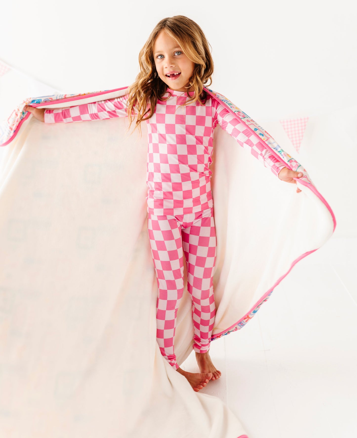 Child wearing pink checkered bamboo pajamas with a plush blanket wrapped around her