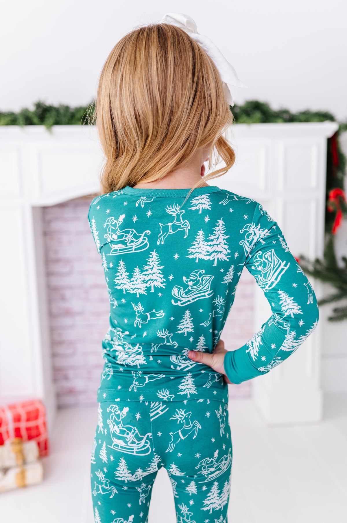 The back view of a little girl wearing bamboo pajamas featuring a vintage sleigh print 