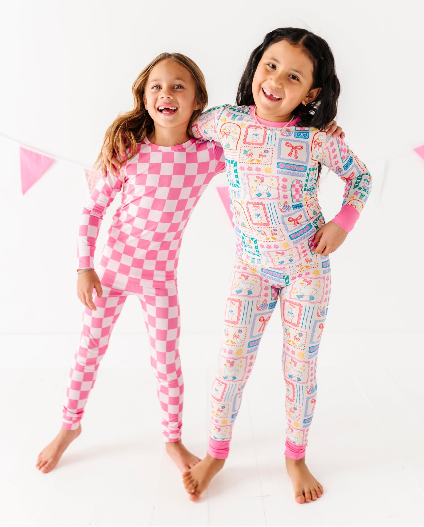 Two children wearing pink and multicolored bamboo pajamas on a white background