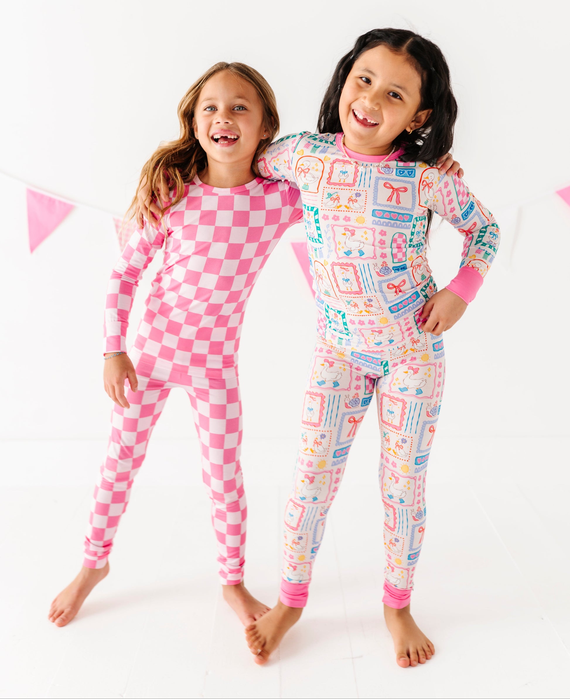 Two children wearing pink and multicolored bamboo pajamas on a white background