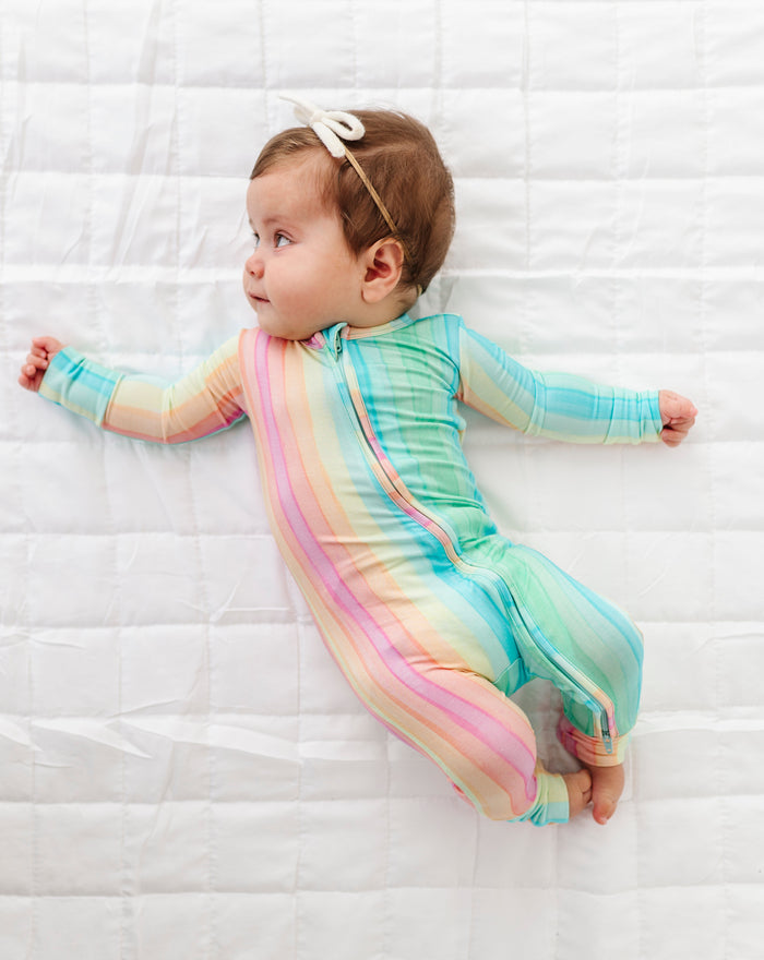 Baby lying down in rainbow stripe convertible footie romper with fold over mitts and cozy fit