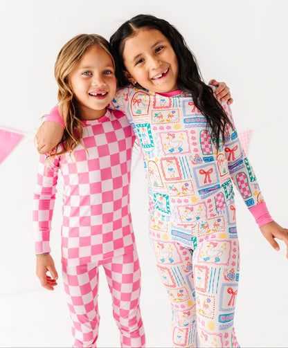 Two children wearing pink bamboo pajamas with different patterns on a white background