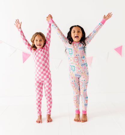 Two children wearing colorful bamboo pajamas with their arms raised against a white background