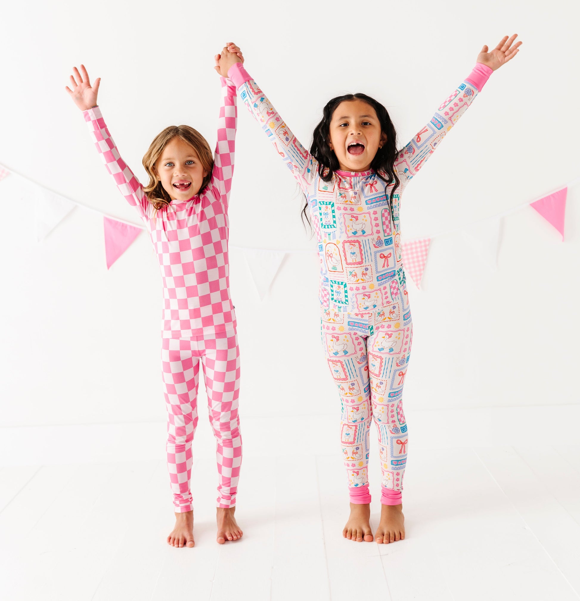 Two children wearing colorful bamboo pajamas with their arms raised against a white background
