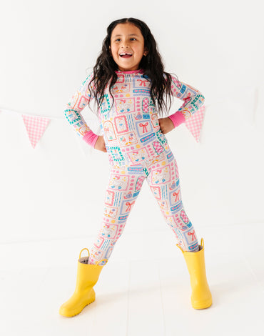 Child wearing a colorful patterned onesie with yellow boots on a white background