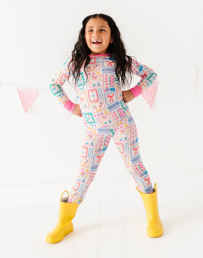 Child wearing a colorful patterned onesie with yellow boots on a white background