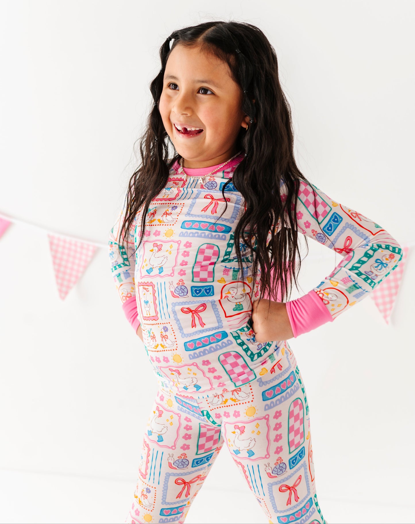 Child wearing a colorful pajama set with a pattern of letters and shapes on a white background