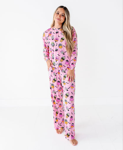 A woman modeling a pink long-sleeve pajama set with a colorful cartoon owl pattern, standing against a plain white studio background.