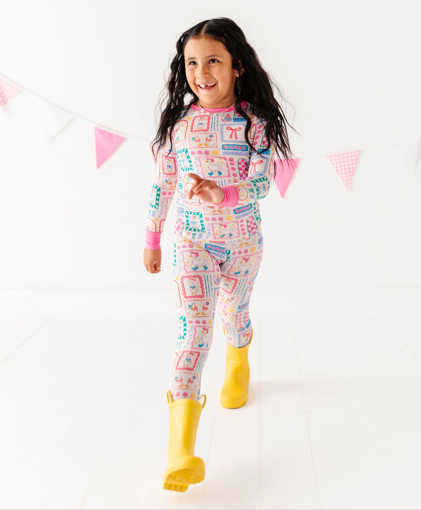 Child wearing colorful bamboo pajamas with yellow rain boots on a white background