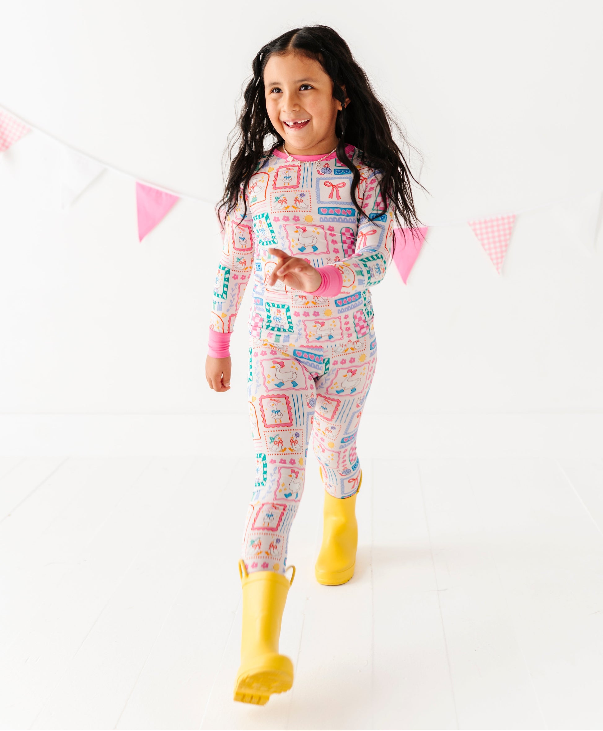 Child wearing colorful bamboo pajamas with yellow rain boots on a white background