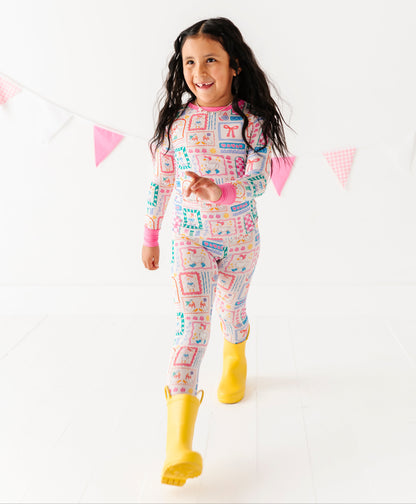 Child wearing colorful bamboo pajamas with yellow rain boots on a white background