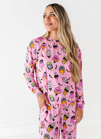 A woman modeling a pink long-sleeve pajama set with a colorful cartoon monster print, photographed against a plain white studio background.