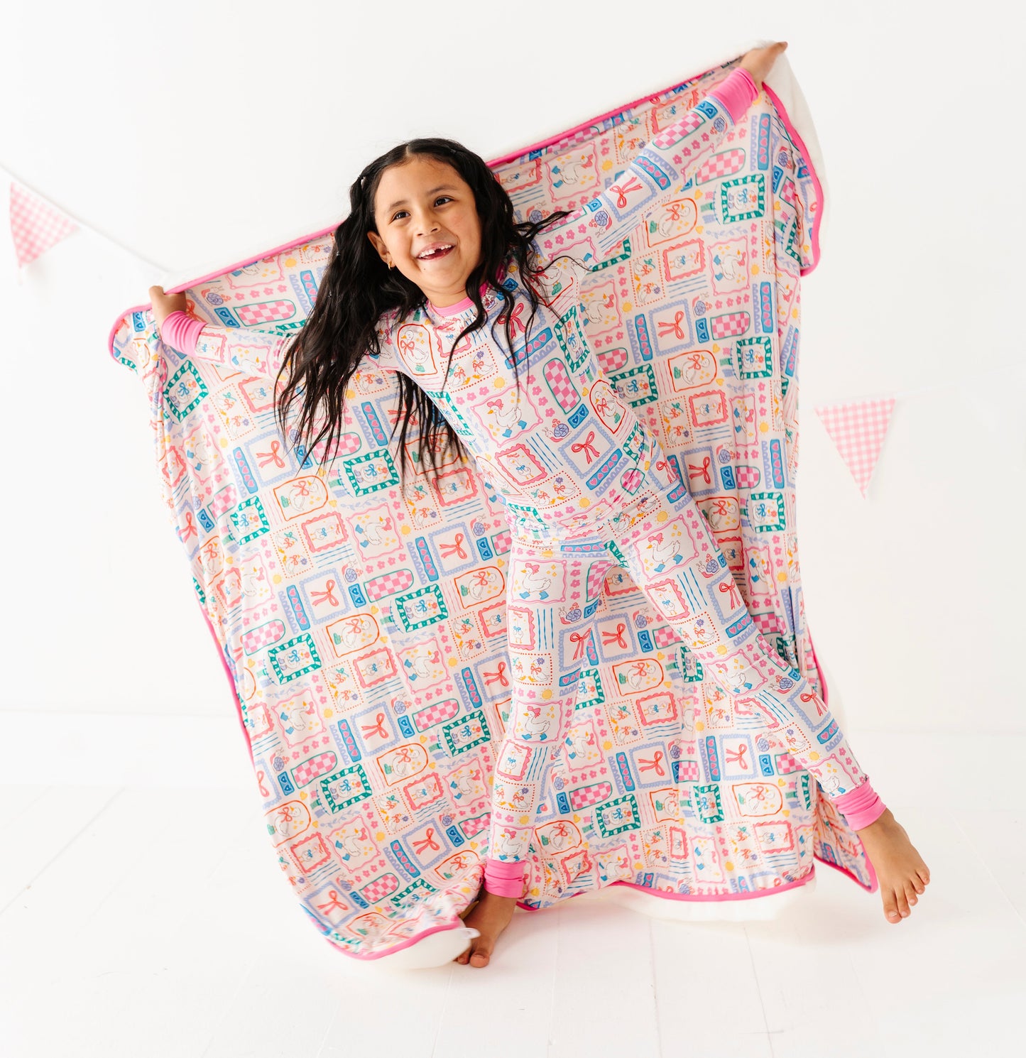 Child holding a colorful bamboo blanket with geese patterns on a white background