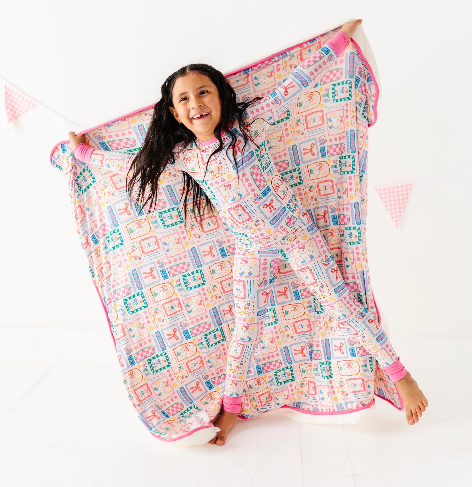 Child holding a colorful bamboo blanket with geese patterns on a white background