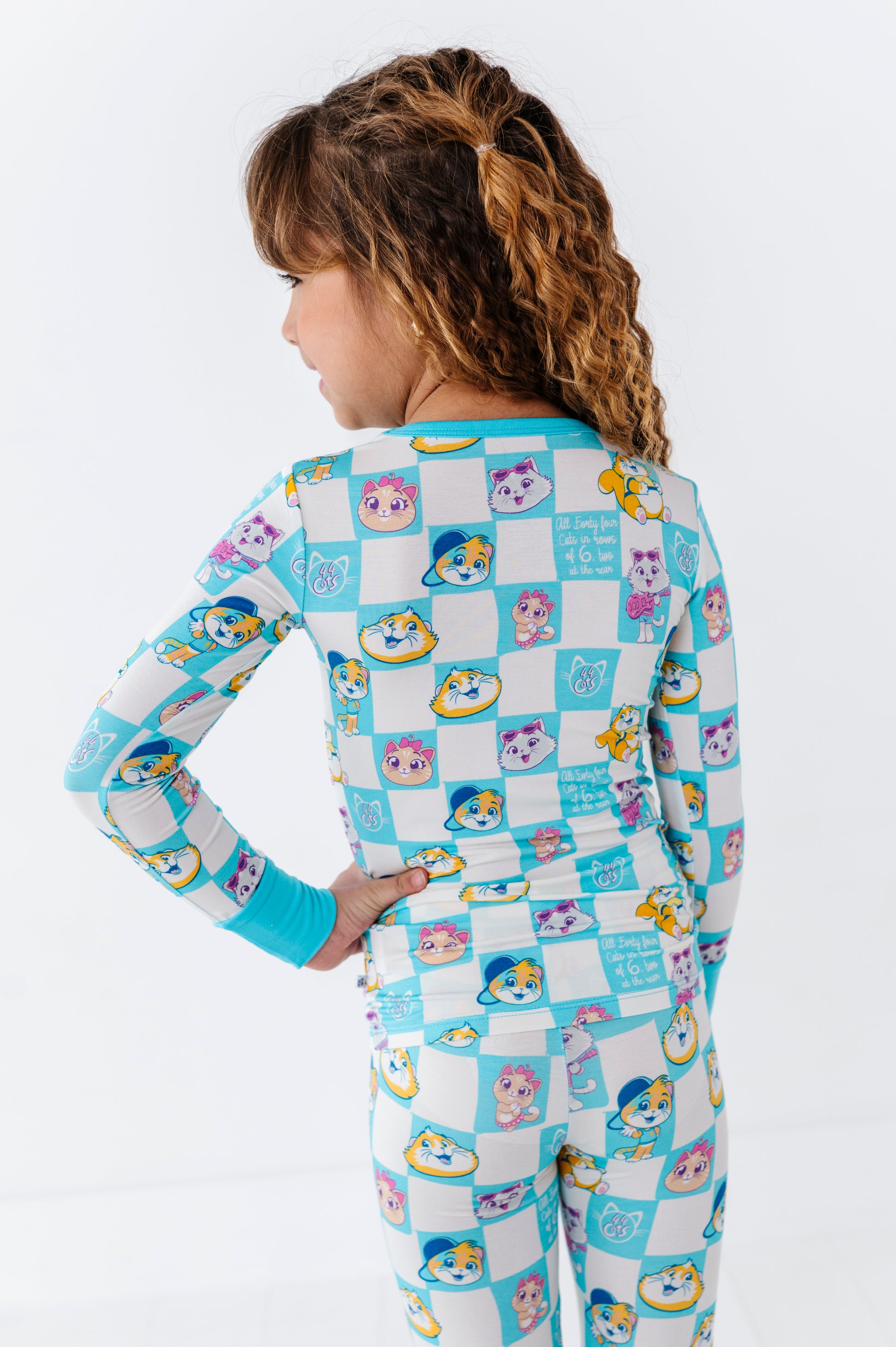 Child wearing an officially licensed 44 Cats bamboo pajama set with cartoon cats on a white background