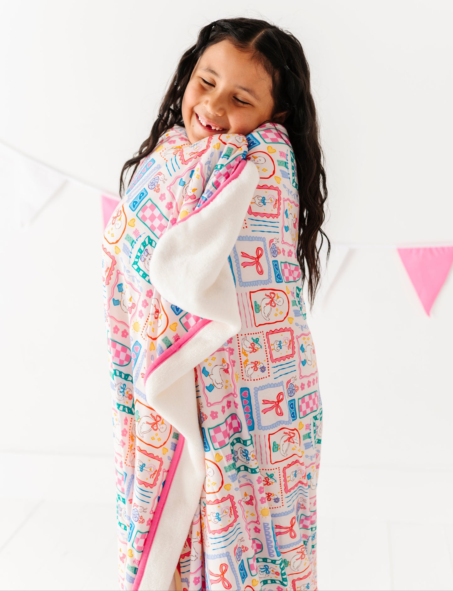 Child wrapped in a colorful plush blanket with a white background