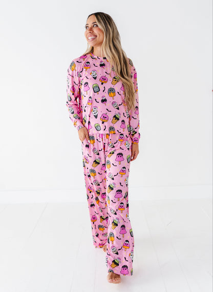 A woman modeling a pink long-sleeve pajama set with a colorful cartoon character print, standing against a plain white studio background.