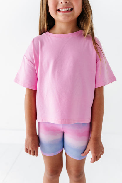 Child wearing a pink shirt and multicolored bamboo shorts on a white background