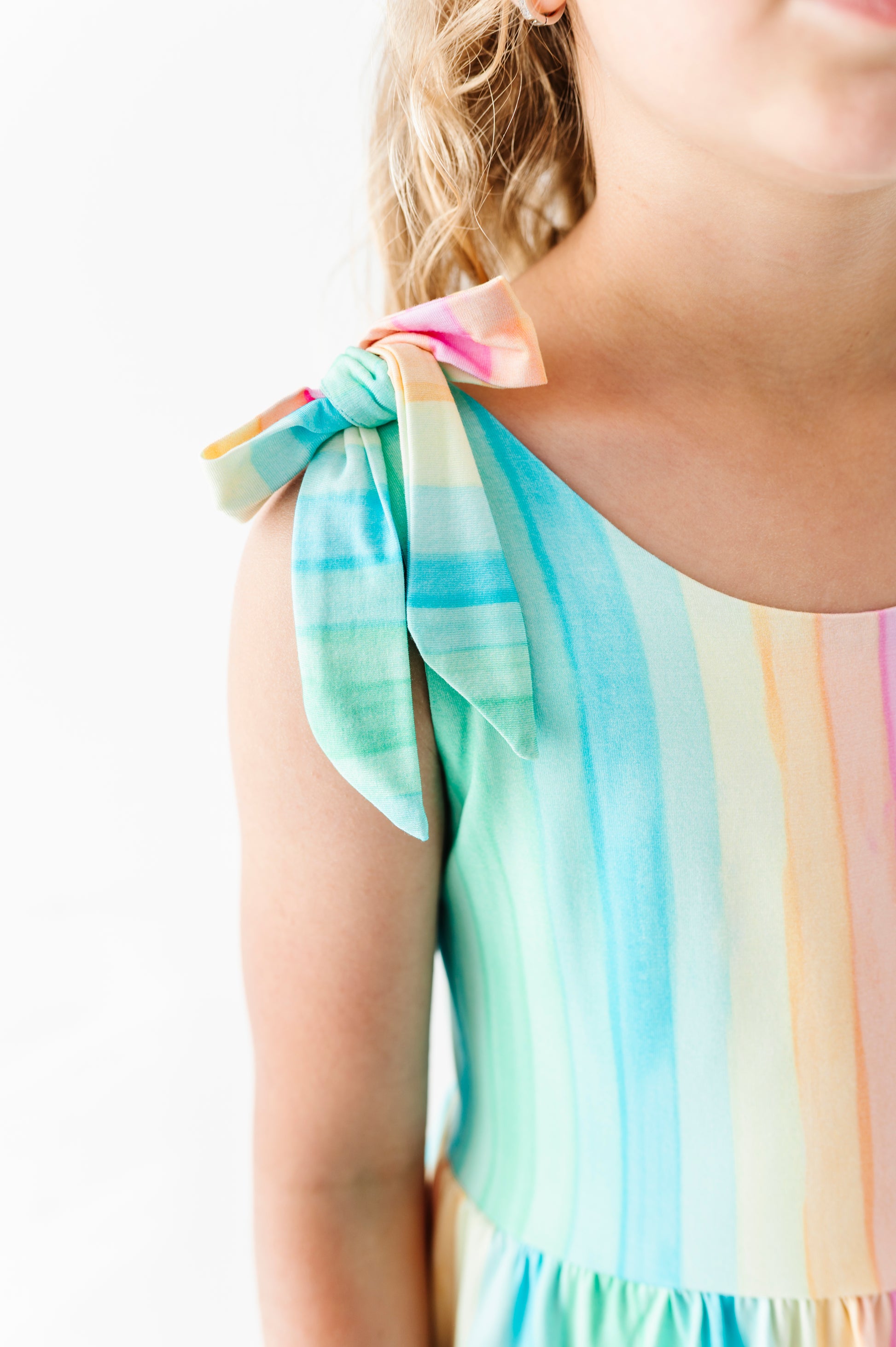 Child wearing a colorful striped romper with a white background