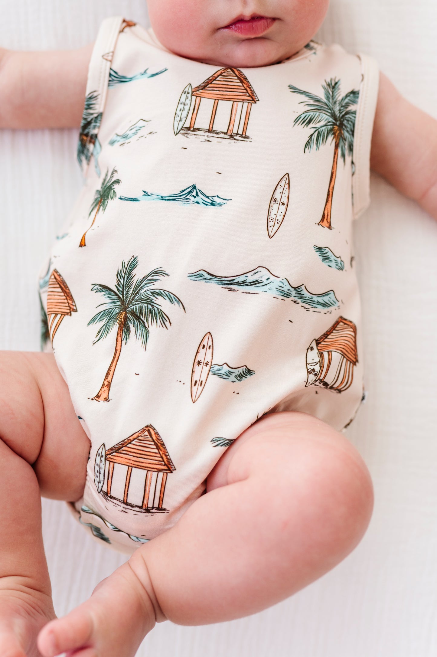 Baby wearing a sleeveless onesie with beach-themed print
